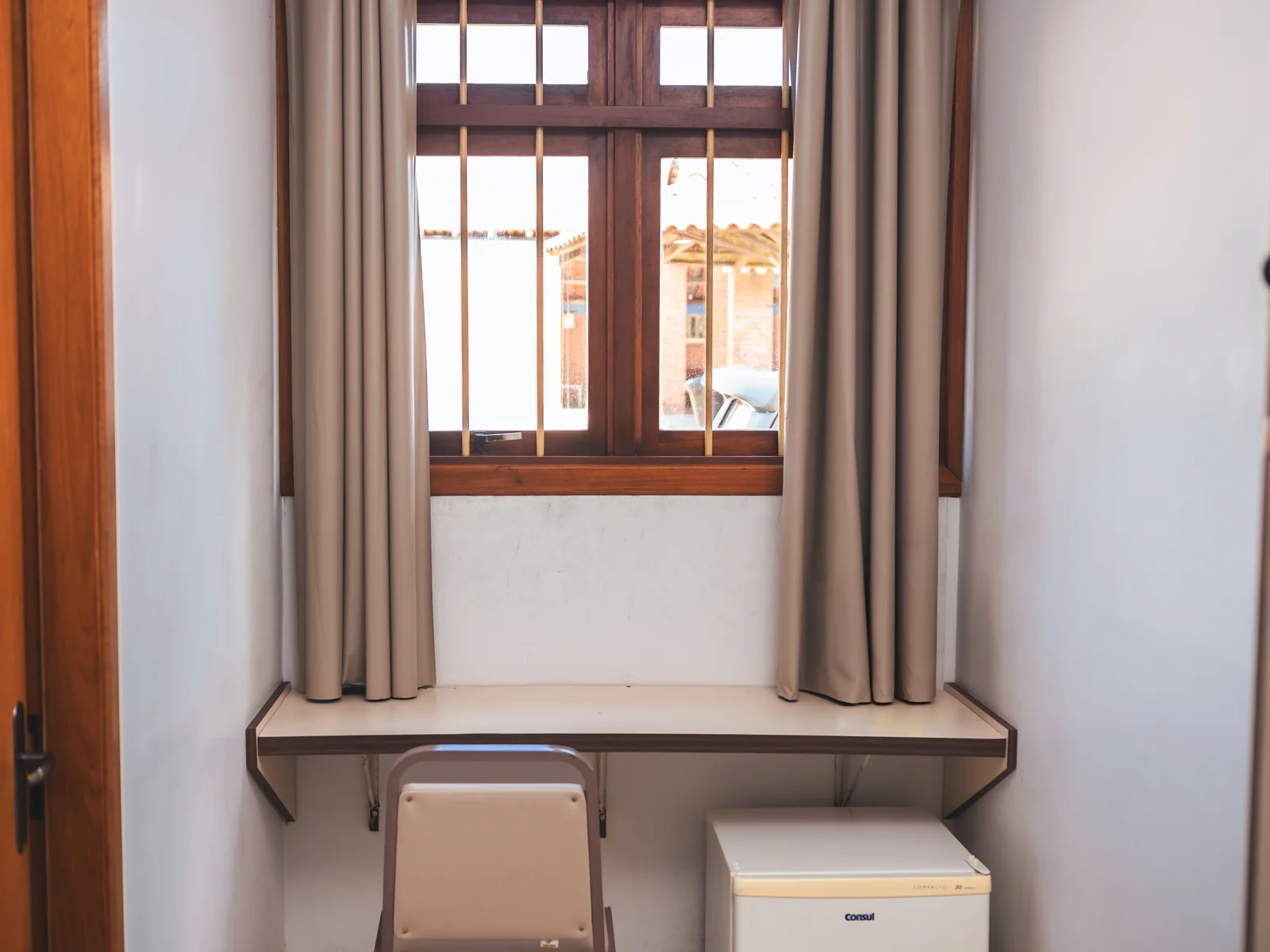 Bancada de trabalho com cadeira, janela e frigobar em Apartamento Econômico do Sítio Hotel & Eventos